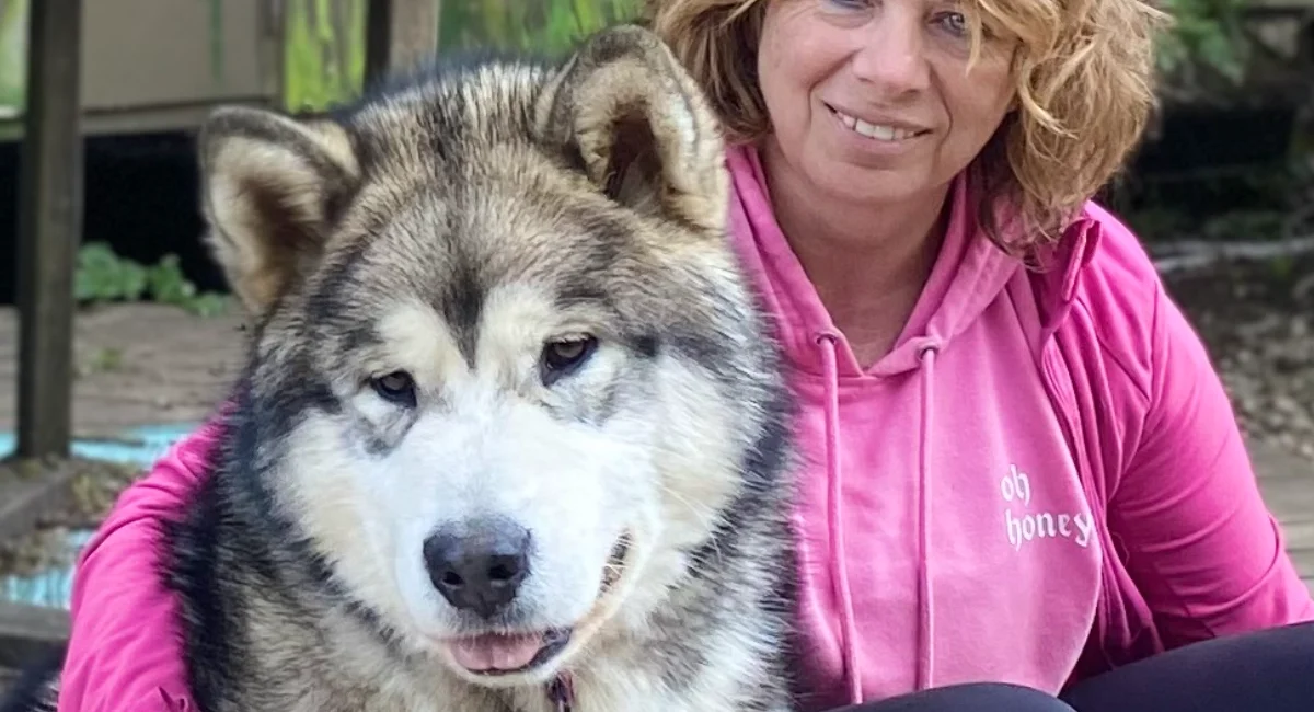 Owner of Souvenir of Sitkas sitting with Malamute